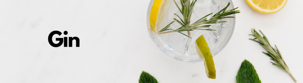 Glas med gin set fra oven, pyntet med ingredienser og ordet Gin fremgår til venstre